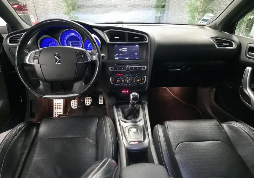 Intérieur noir cuir du DS4 2016 vu de face, avec tableau de bord éclairé en bleu et levier de vitesses manuel.