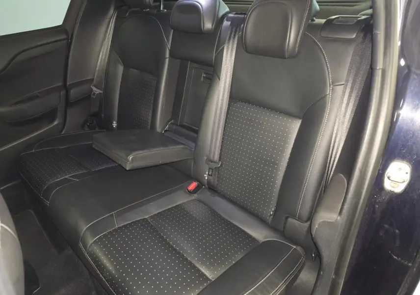 Vue intérieure sur la banquette arrière en cuir noir perforé du DS4 violet, avec accoudoir central déployé.