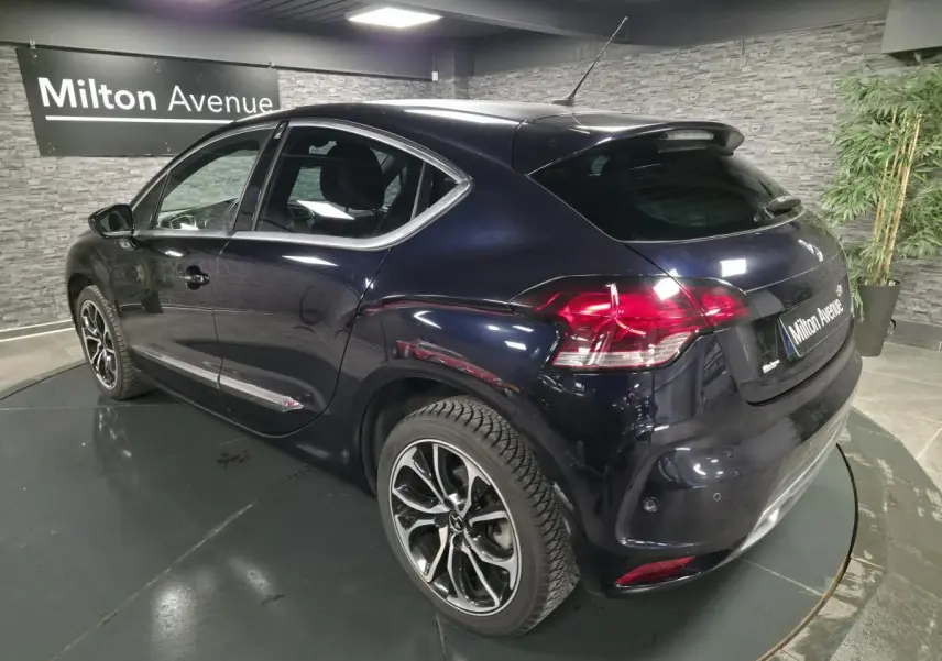 Vue 3/4 arrière droite d'une DS4 violet foncé métallisé avec jantes alliage noires et baguettes chromées.