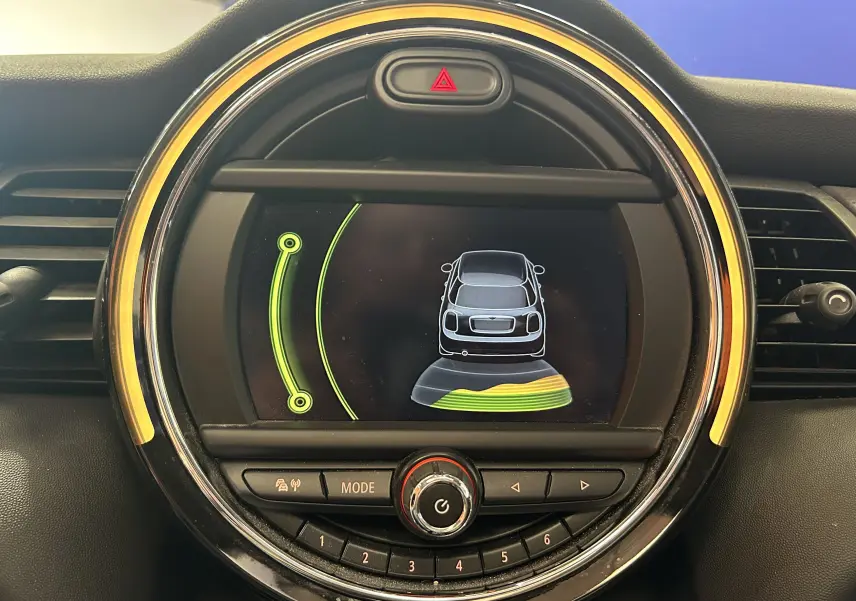 Affichage du tableau de bord MINI Cooper D 2015 montrant l'aide au stationnement avec cercles verts et jaunes autour de l'écran rond.