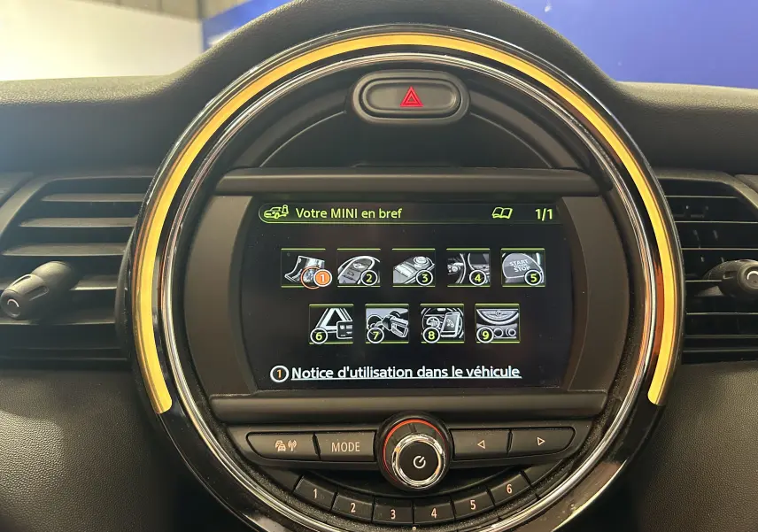 Vue rapprochée de l’écran central rond du tableau de bord d’une MINI Cooper D 2015 avec éclairage orange autour.