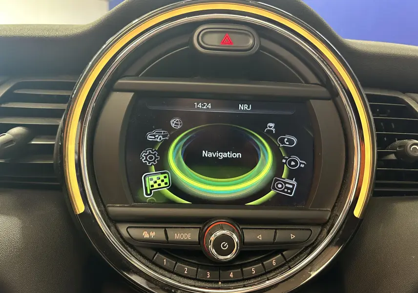 Vue rapprochée du tableau de bord de la MINI 5P Cooper D 2015, écran central rond avec interface navigation et éclairage ambre.