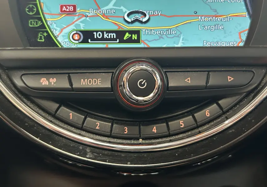 Gros plan sur la console centrale du MINI 5P Cooper D bleu de 2015, montrant les commandes du mode de conduite et l'écran GPS.