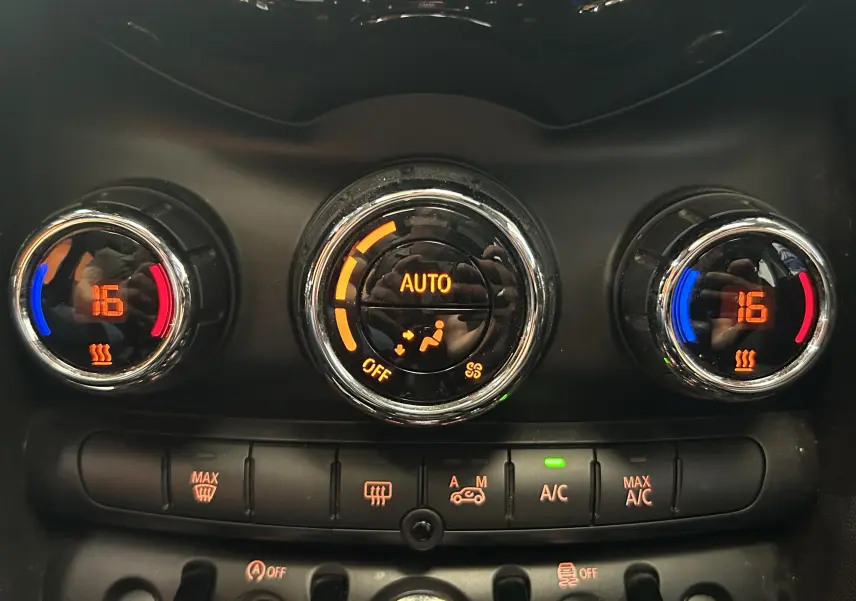 Gros plan sur les commandes de climatisation automatique de la MINI 5P bleu, affichant 16°C côté gauche et droit.