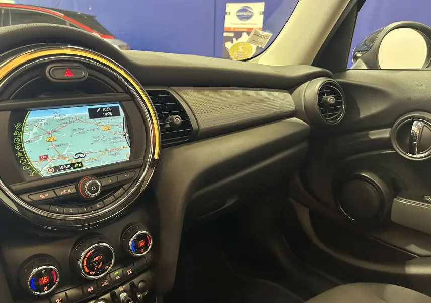 Vue intérieure côté passager de la MINI 5P Cooper D 2015, avec tableau de bord noir et écran GPS central lumineux.