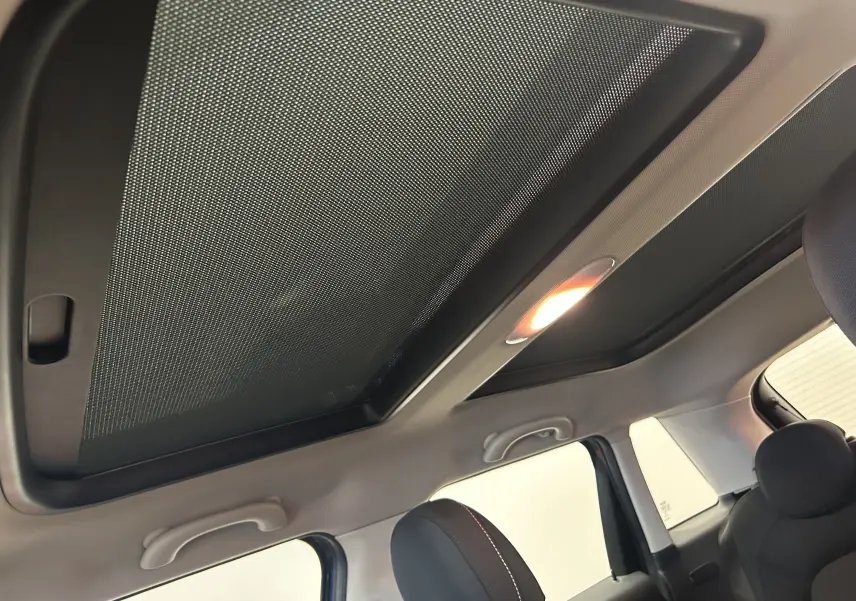 Vue intérieure du toit ouvrant avec pare-soleil en tissu et éclairage intérieur de la MINI 5 portes bleu.
