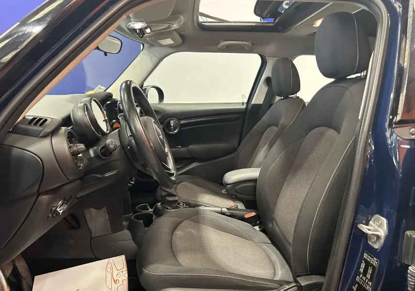 Vue intérieure côté conducteur de la MINI 5P Cooper D bleu, avec sièges tissu et toit ouvrant visible.