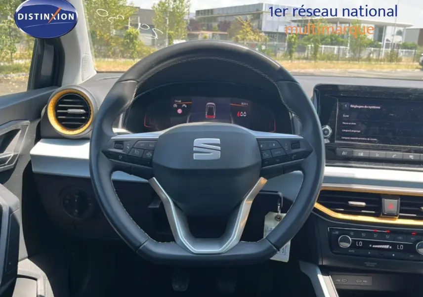 Vue intérieure centrée sur le volant de la SEAT Arona gris Magnetic, avec tableau de bord digital et détails dorés.
