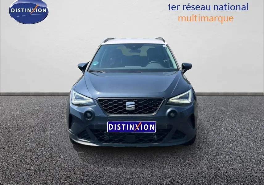 Vue frontale d'un SEAT Arona gris Magnetic Metal avec toit blanc, affichant ses phares LED allumés et calandre noire.
