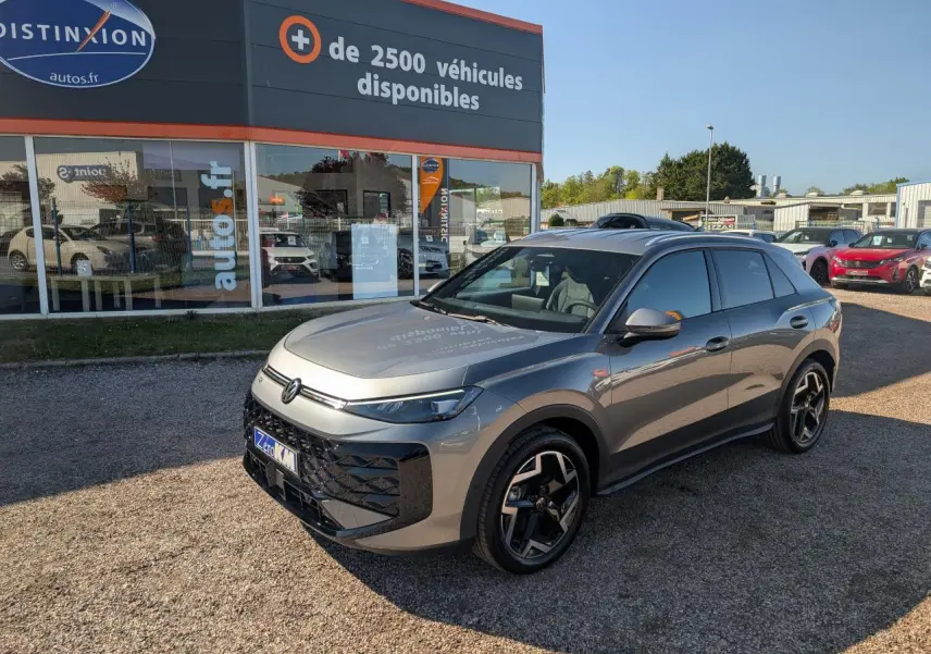 Volkswagen T-Roc gris métallisé vu en 3/4 avant droit, avec jantes 18 pouces et toit noir.