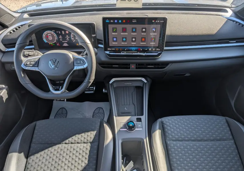 Vue intérieure avant du Volkswagen T-Roc 2026 avec tableau de bord numérique et écran tactile central, sièges tissu R-Line gris.