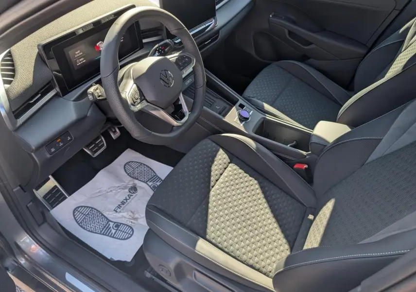 Vue intérieure côté conducteur du Volkswagen T-Roc 2026, sièges tissu R-Line noirs avec volant multifonction cuir.