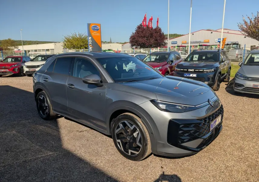 Volkswagen T-Roc gris métallisé en 3/4 avant droit avec jantes noires et calandre R-Line distinctive.