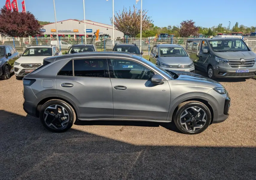 Volkswagen T-Roc gris métallisé vu de profil côté gauche, avec jantes noires et vitres surteintées.