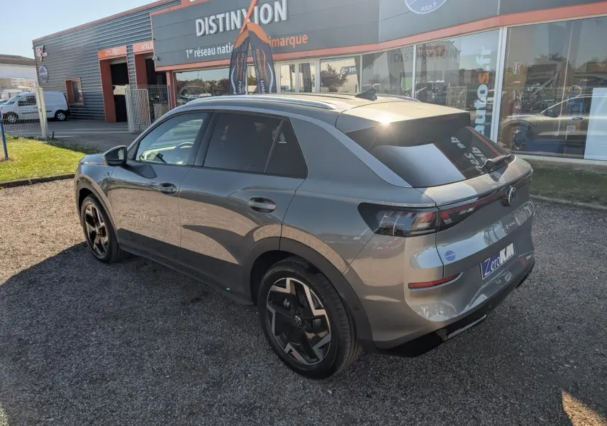 Volkswagen T-Roc gris métallisé vu en 3/4 arrière droit, avec jantes noires et vitres arrière surteintées.