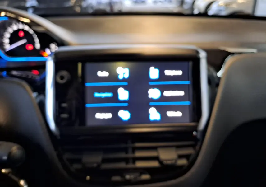 Vue floue du tableau de bord et de l'écran tactile central d'un Peugeot 2008 gris, version Crossway 2019.