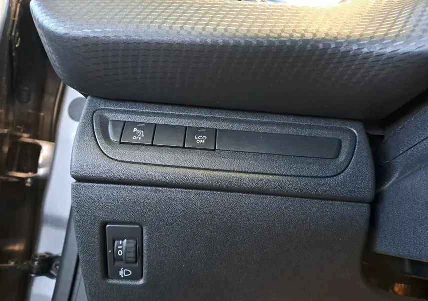 Gros plan sur les commandes de la console côté conducteur du Peugeot 2008 gris, avec boutons de désactivation parking et mode Eco.