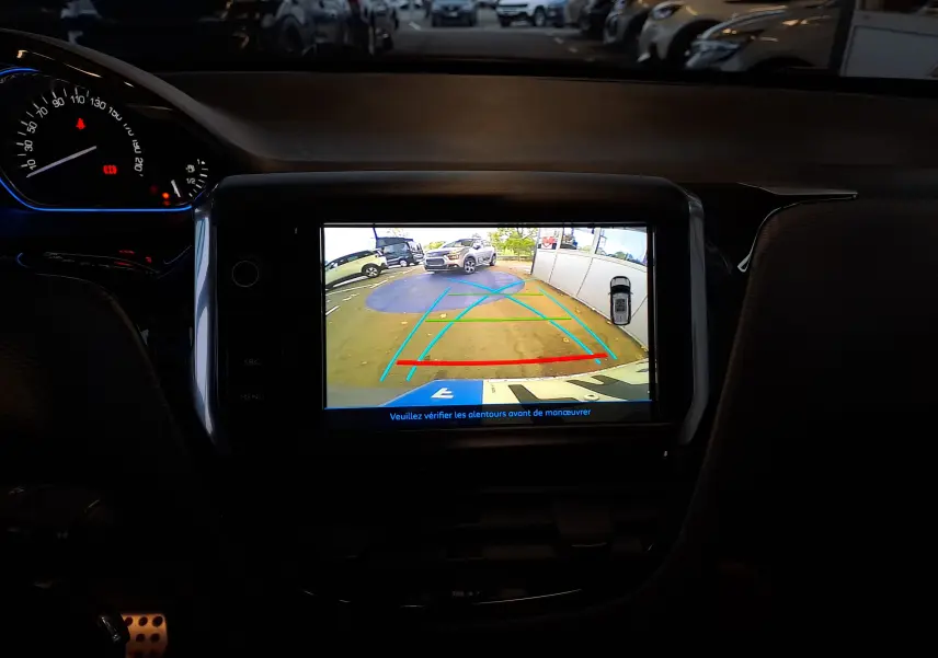 Vue intérieure du tableau de bord du Peugeot 2008 gris 2019, avec écran de caméra de recul affichant l'arrière du véhicule.