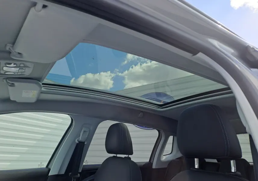 Vue intérieure du toit ouvrant panoramique et des sièges noirs du Peugeot 2008 gris 2019, côté gauche ouvert.
