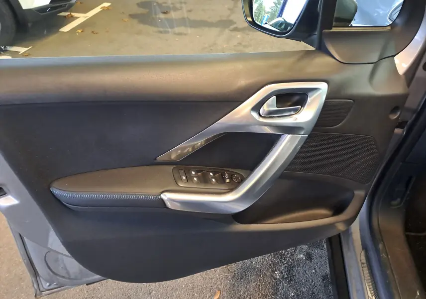 Vue côté gauche de la porte avant grise d'un Peugeot 2008 2019, avec commandes électriques et poignée argentée.