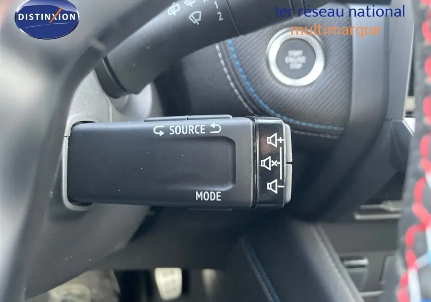Gros plan sur la commande audio au volant et bouton start/stop avec surpiqûres bleues dans l'habitacle gris du Renault Symbioz.