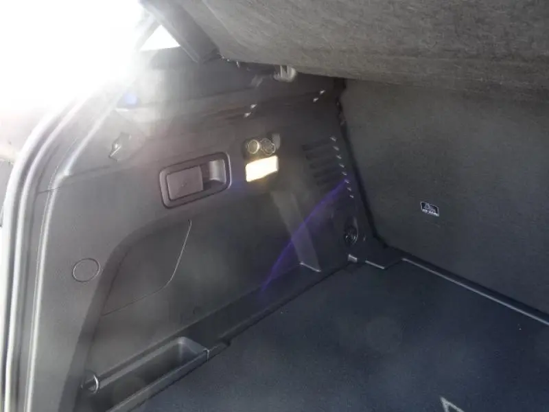 Vue intérieure du coffre du Peugeot 3008 gris clair, montrant une prise 12V et un éclairage latéral.