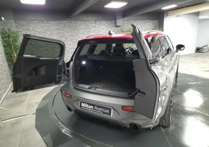Vue arrière ouverte d'une MINI Clubman gris métallisé avec portes de coffre papillon dans un garage.