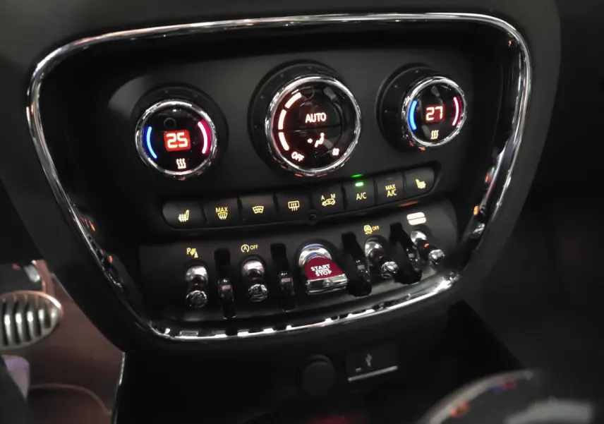 Gros plan sur la console centrale de la MINI Clubman John Cooper Works 2020, avec commandes climatisation bi-zone et bouton start/stop rouge.