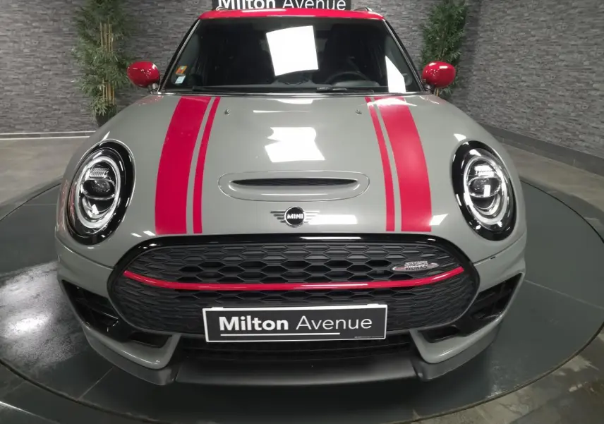 Vue frontale d'une MINI Clubman gris Moonwalk avec bandes rouges sport et calandre noire John Cooper Works.