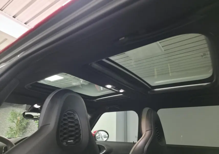 Vue intérieure du toit ouvrant panoramique et des sièges avant en cuir noir du MINI Clubman John Cooper Works gris.