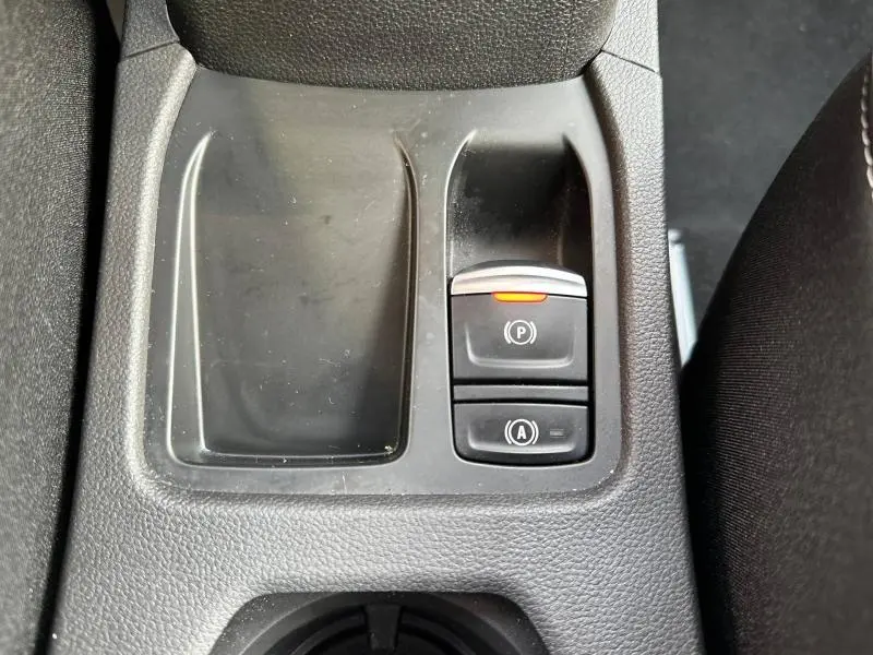 Gros plan sur la console centrale de la Renault Clio 2025, montrant les boutons du frein à main électrique et de l'arrêt automatique.