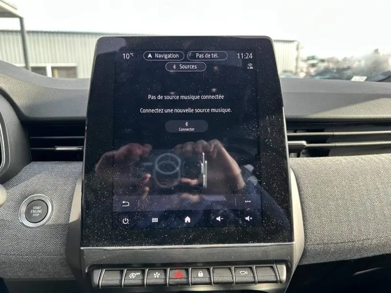 Écran tactile central du tableau de bord de la Renault Clio 2025, avec bouton Start/Stop et finition tissu gris.