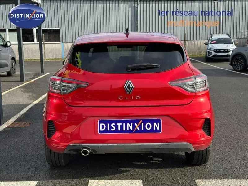 Vue arrière d'une Renault Clio 1.0 TCe 90ch Techno rouge flamme, avec feux LED et sortie d'échappement visible.