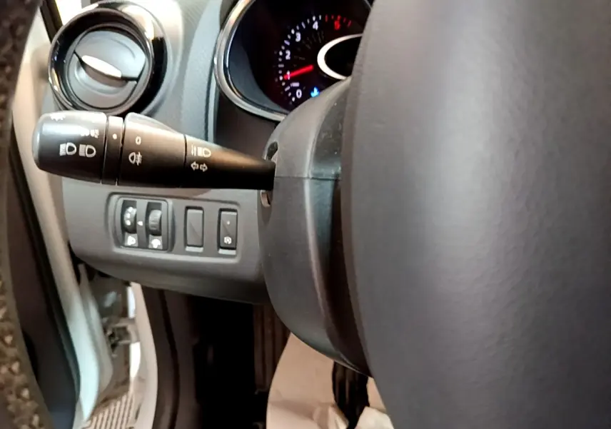 Vue rapprochée du volant cuir et des commandes d'éclairage à gauche dans une Renault Clio Zen Energy dCi 75 blanche de 2016.