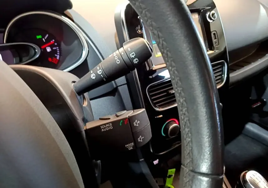 Vue rapprochée de l’intérieur de la Renault Clio blanche, volant cuir multifonctions et tableau de bord avec écran tactile.