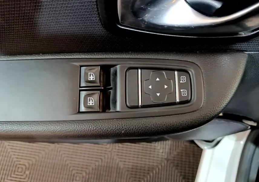 Gros plan sur les commandes de lève-vitres et réglage des rétroviseurs côté conducteur d’une Renault Clio blanche 2016.