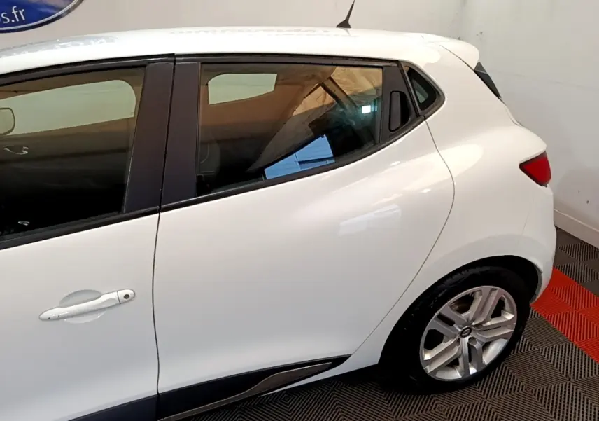 Profil arrière droit d'une Renault Clio Zen Energy dCi 75 blanche, avec poignées de porte intégrées et jantes alliage visibles.