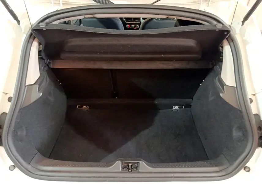 Vue arrière du coffre ouvert d'une Renault Clio blanche, montrant l'espace de chargement et la banquette arrière.