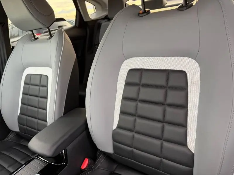 Gros plan sur les sièges avant gris clair et noir du Citroën C4 X 2025 avec détails en tissu et cuir, intérieur moderne.