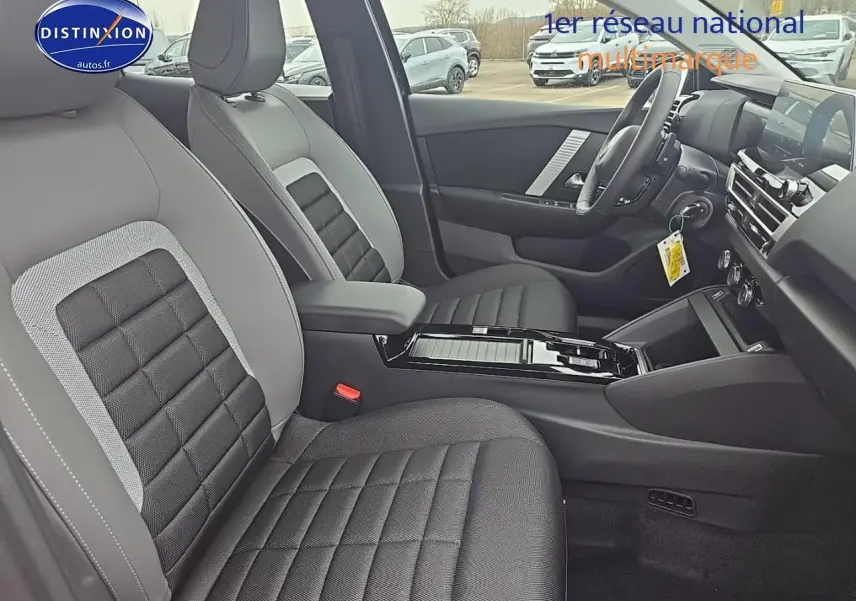 Vue intérieure côté droit de la Citroën C4 1.2 hybride 136 plus, sièges tissu noir et gris avec console centrale brillante.