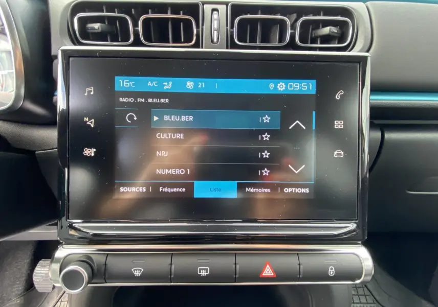 Écran tactile central de la Citroën C3 2021 noir, affichant la liste des stations radio avec commandes climatisation en dessous.