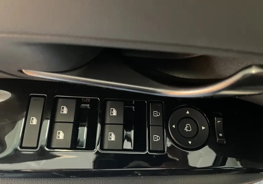 Gros plan sur les commandes de lève-vitres et réglages des rétroviseurs côté gauche d'un Hyundai Tucson gris Ecotronic 2025.