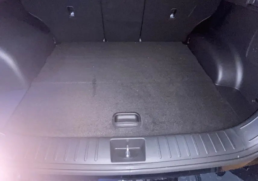 Coffre spacieux vu de l'arrière ouvert du Hyundai Tucson 2025 gris Ecotronic, avec plancher plat et garnitures noires.