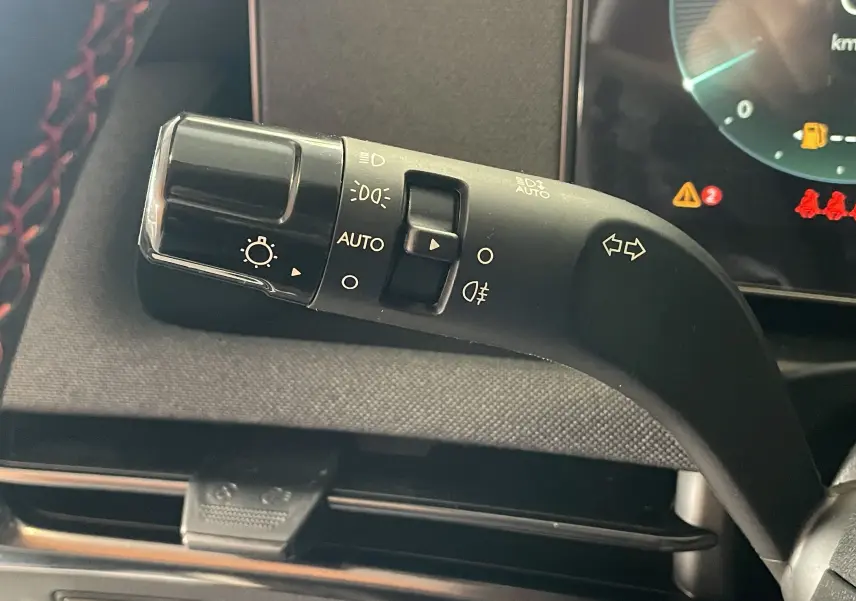 Gros plan sur la manette de clignotants noire avec commandes d'éclairage du Hyundai Tucson gris Ecotronic 2025.
