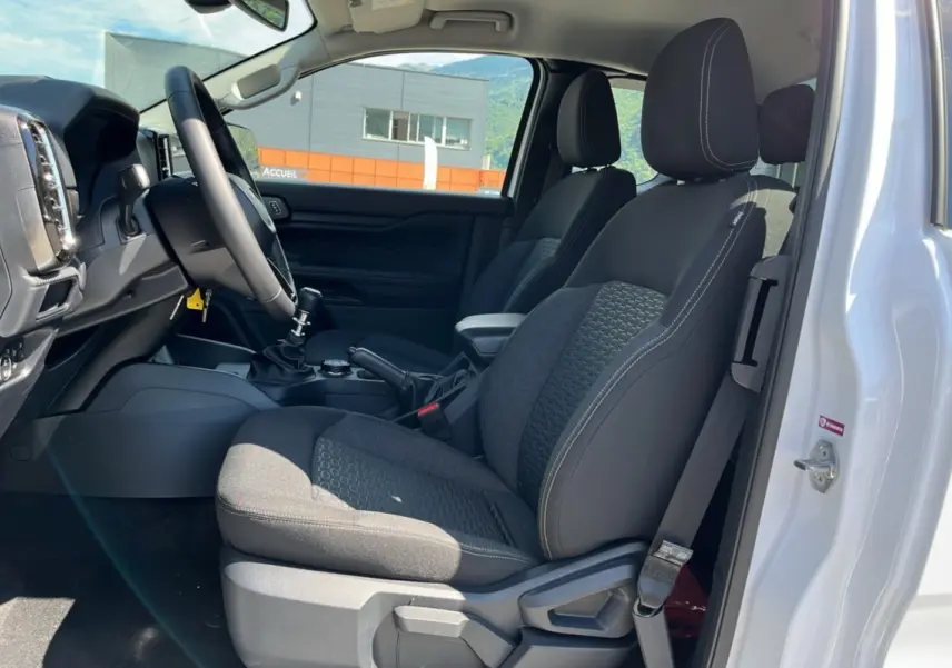 Vue intérieure côté conducteur du Ford Ranger gris iconic 2025, montrant les sièges avant et le volant cuir multifonctions.