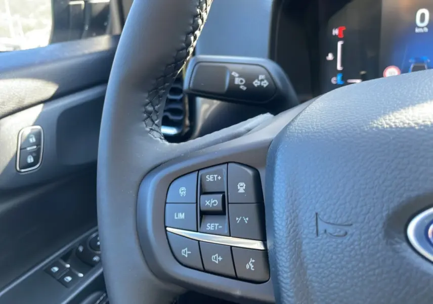 Gros plan sur le volant cuir multifonctions du Ford Ranger 2025, avec commandes intégrées et tableau de bord partiel visible.
