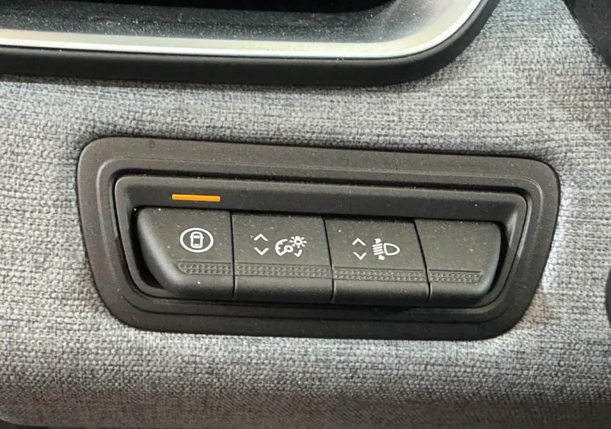 Gros plan sur les commandes de réglage du tableau de bord et des phares dans l’habitacle gris clair de la Renault Clio 2025.