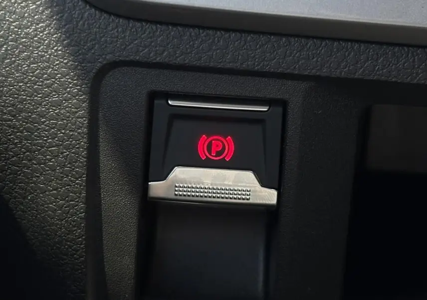 Gros plan sur le bouton de frein de stationnement électrique rouge dans l'habitacle noir du Citroën Jumpy.