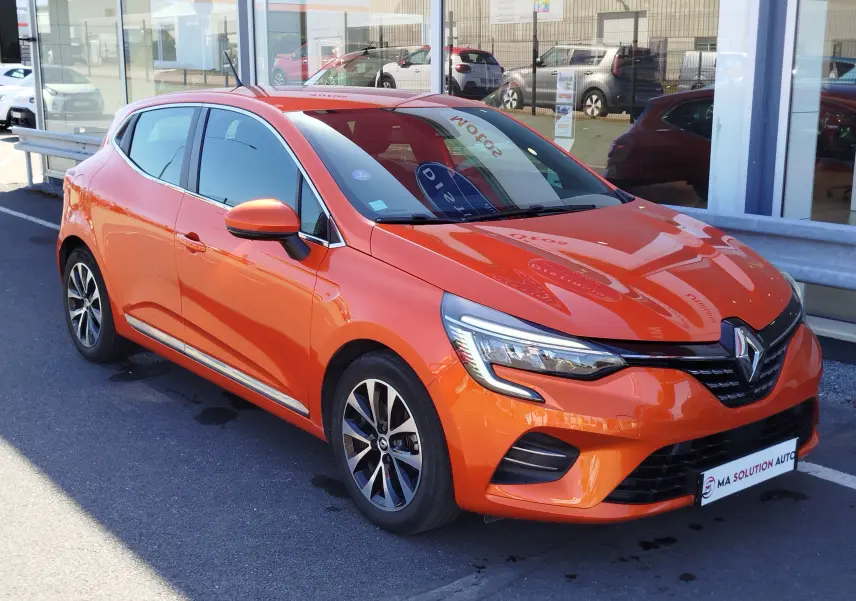 Renault Clio 1.6 E-Tech hybride orange Valencia vue 3/4 avant droit, avec jantes alliage et feux LED distinctifs.