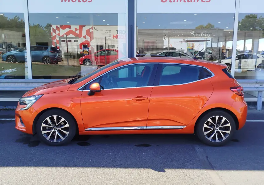 Profil côté gauche de la Renault Clio 1.6 E-Tech hybride 140ch Intens 2022 en Orange Valencia, avec jantes alliage et vitres teintées.